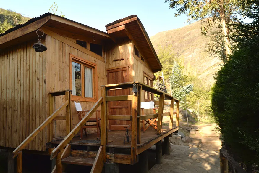 Exterior de la cabaña Eucaliptus, de madera y con terraza, al pie del cerro