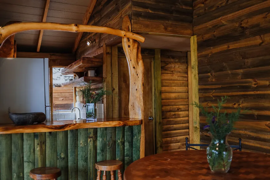 Barra de cocina en madera nativa con encimera de tronco y arco de rama natural, en la cabaña Nogal