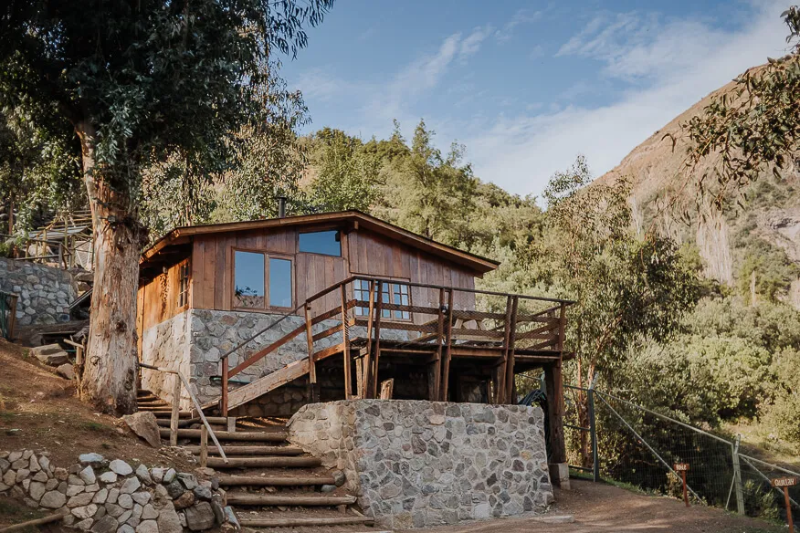 Exterior de la cabaña Roble, sobre base de piedra y con terraza en alto, entre eucaliptos